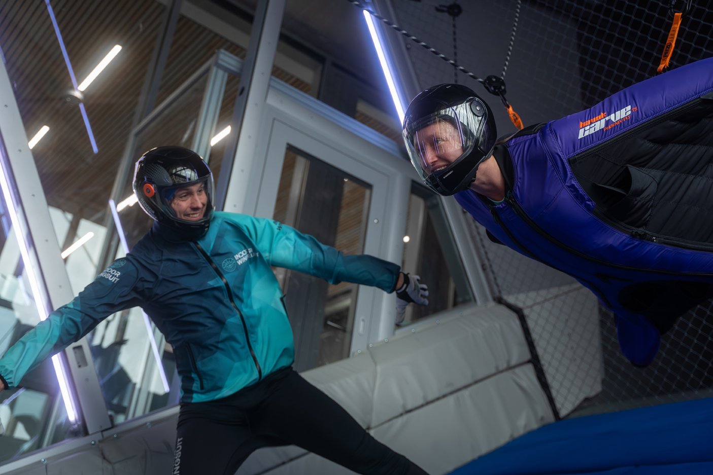Wingsuit flyer being guided by an instructor in Inclined's wind tunnel